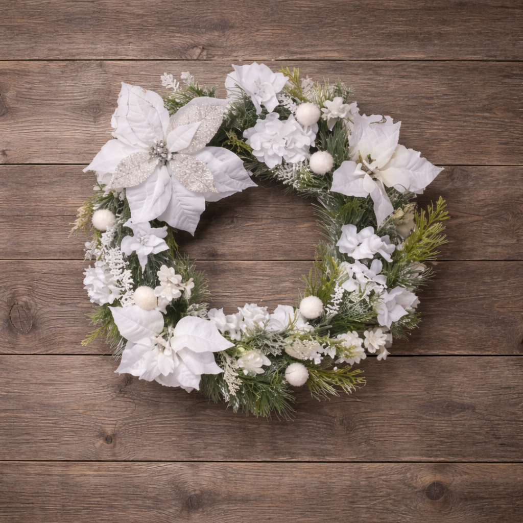 Handmade winter wreath with white poinsettias, frosted greenery, and soft white accents displayed on a natural wood background.